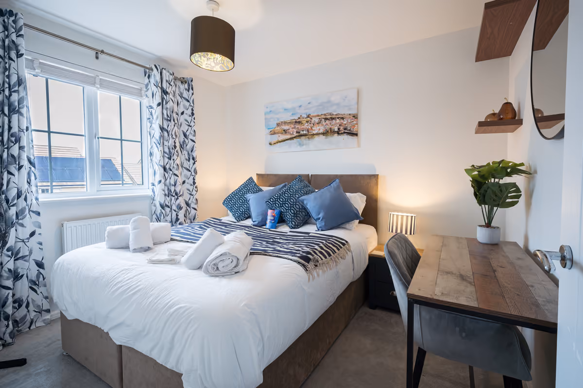 Double bedroom with king bed, desk and blue cushions