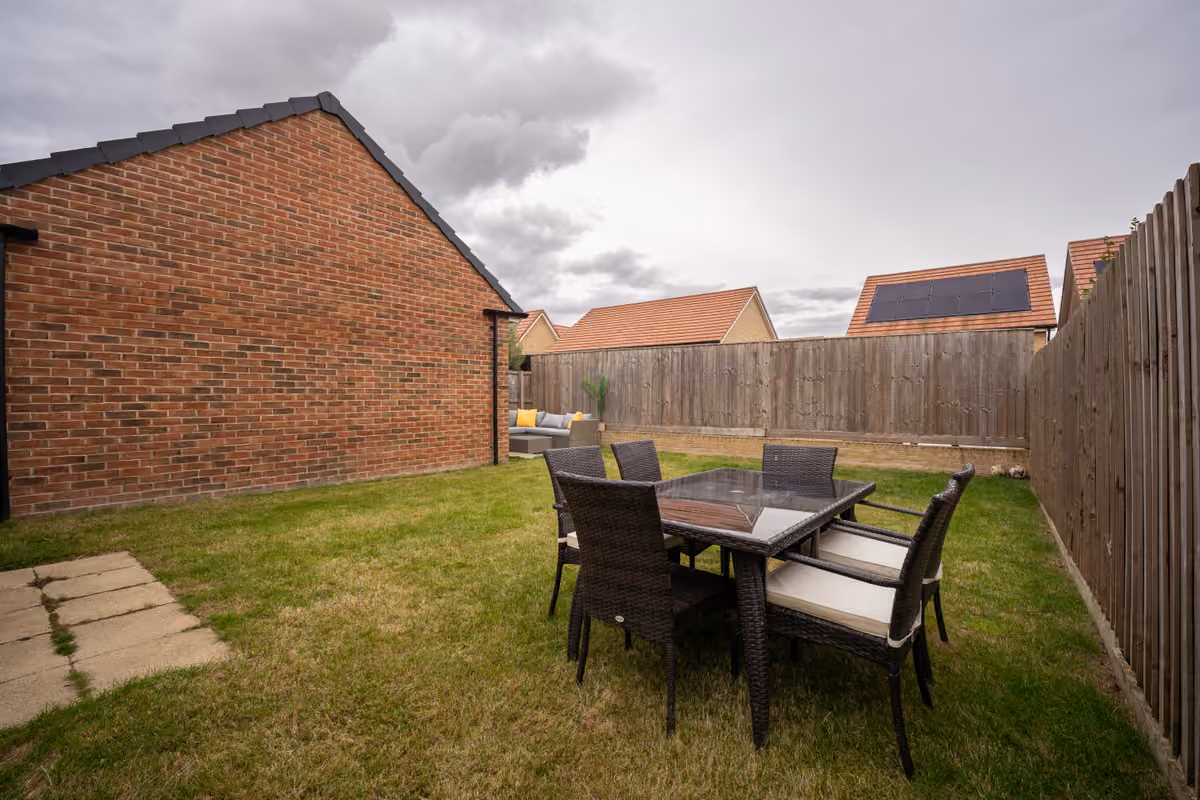 Enclosed rear garden with lawn and outdoor dining set